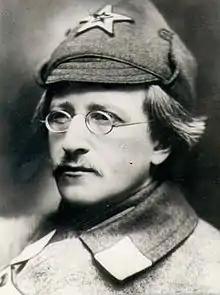 Portrait photograph of Vladimir Antonov-Ovseenko, wearing a Red Army officer cap and jacket, a moustache and glasses