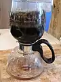 Step 5: At this point, the coffee has been fully brewed, but still contains the coffee grounds. The glass carafe is taken off the heated surface.