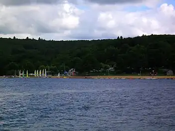 Leisure beach on the south side of the lake, with typical Plateau de Millevaches landscape in the background