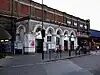 A white building with a rectangular, white sign reading "Vauxhall" in black letters and four bicycles in front all under a grey sky