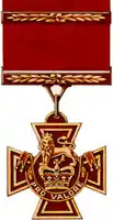 A bronze cross pattée bearing the crown of Saint Edward surmounted by a lion with the inscription Pro Valore. A Bar crosses the crimson ribbon attached to the medal.