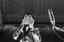 A black and white photo of singer Vince Taylor in front of a microphone