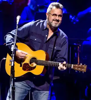 Country music singer Vince Gill, strumming an acoustic guitar