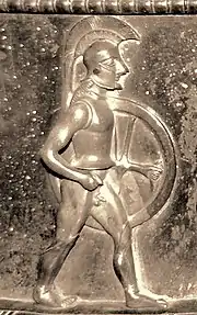 Relief of a soldier in profile, wearing a crested helmet and carrying a circular shield