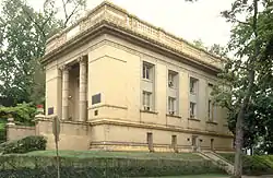 An oblique view of a large salmon colored two story neoclassical style stone building, of some prominence.