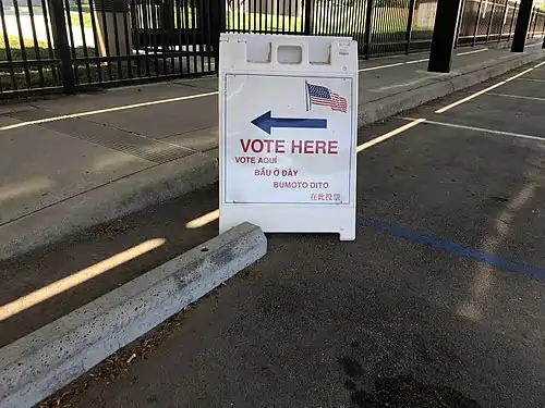 A sign directing voters to a voting location in English, Vietnamese and some other languages