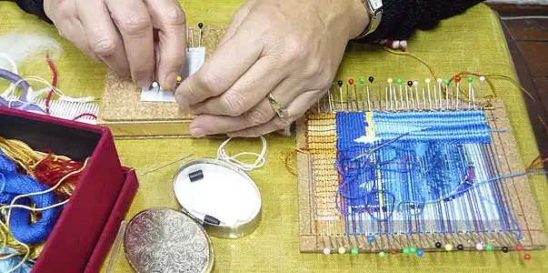 Weaving by wrapping the warp and weft threads between pins stuck into a pinnable surface (in this case, cork; foamcore is also used.).