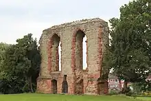 A fragment of a grey sandstone wall containing two large upper windows and two smaller lower ones, each decorated with red sandstone