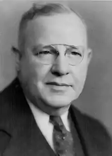 A black and white portrait of Webber in a suit and tie