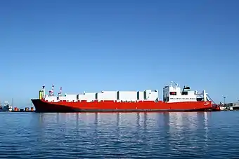 The MV Tampa vessel, a large container-cargo ship with a red hull in a harbour.