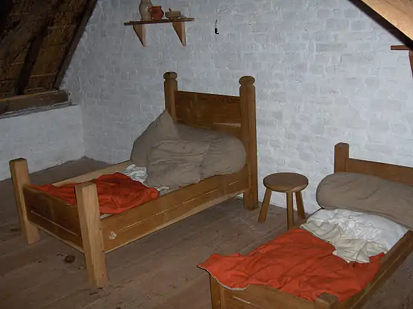 Medieval-reconstruction rope beds (circa 1465, Belgium, northern Europe). Note loops of rope protruding from side boards. With mattrasses, the large pillows then fashionable, linen pillowcases and sheets, and madder-dyed red blankets.