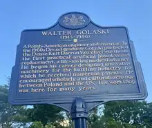 A blue metal sign with the state seal of Pennsylvania above it that reads: "Walter Golaski (1913–1996). A Polish-American engineer and inventor. In the 1960s Drexel graduate Golaski perfected the Dense Knit Dacron Vascular Prosthesis, the first practical artificial blood vessel replacement, a life-saving medical advance. He began his career designing innovative machinery for the knitting industry, for which he received numerous patents. He encouraged scholarly and cultural exchange between Poland and the US. His workshop was here for many years." In tiny letters below that: "PENNSYLVANIA HISTORICAL AND MUSEUM COMMISSION 20140"