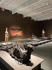 A photo of a section of the exhibition "Wangechi Mutu: Intertwined" at New Museum taken in March 2023. In the photo five different sculpture pieces by Mutu can be seen displayed throughout the gallery, in addition to a collage piece hung on the back wall.