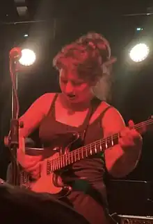 Karly Hartzman from the group Wednesday looks at her electric guitar while playing.