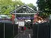 A red-bricked building with a rectangular, dark blue sign reading "WEST FINCHLEY STATION" in white letters all under a light blue sky