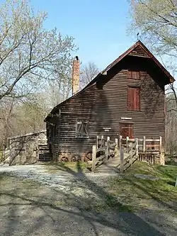 Photograph of a three-story wooden grist mill with a ramp leading to the front door