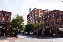 A block of several brick warehouse buildings. One is topped with a blue and white sign with the Paramount mountain logo and arched stars.