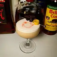 Image 1A whiskey sour, served in a coupe glass, is garnished with a spiral of lemon peel and two maraschino cherries on a cocktail pick, along with drops of bitters swirled into the foam (from egg white) atop the drink. (from Cocktail garnish)