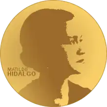 A golden medallion with an  image of Matilde Hidalgo de Procel facing right in profile. To the left of the woman is the text "Matilde" then "Hidalgo"