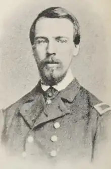 monochrome engraving from photograph, image shows a slim young Caucasian man in naval uniform with dark hair, trimmed beard and mustache