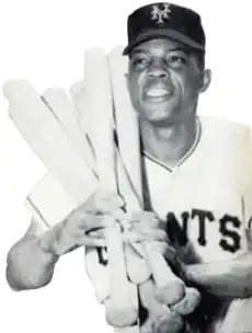 Photograph of Willie Mays in a Giants uniform cradles six bats over his right shoulder