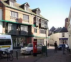 Street scene with buildings and shops. The three-storey building on the left has a sign saying The Courthouse.