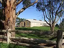 A colour photo of a historic-looking, limestone building appearing through trees in the foreground