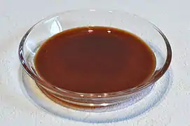 Brown, slightly translucent liquid in a flat, transparent glass dish.