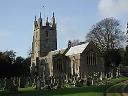 Stone building with square tower. In the foreground are gravestones.