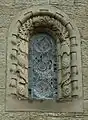 Stone window surround decorated with insects, birds and pinecones