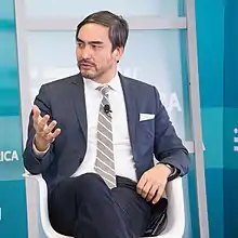 Portrait of Wu speaking at a conference while sitting