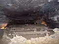 A large room in the cave containing approximately 11 dusty benches.