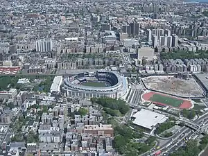 Yankee Stadium (center), Bronx County Courthouse and the Grand Concourse (towards the top), and the site of Yankee Stadium's predecessor to the far right. View is from the northwest, looking to the southeast, with Rikers Island and Queens visible in the upper right corner.