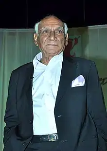 Photograph of Yash Chopra standing and looking to his left