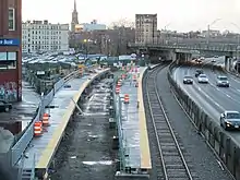 Railway platforms under construction next to an urban highway