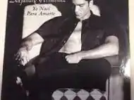 A black-and-white image of a man sitting on a chair with his shirt unbuttoned