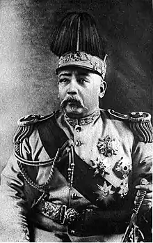 A Chinese man wearing an elaborate military outfit, with a large crown on his head.