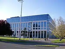 Square glass building surrounded by trees