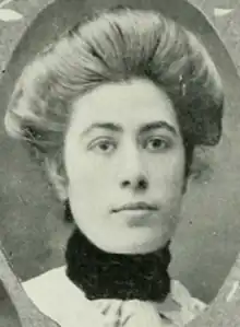 A young white woman with hair in a bouffant updo, wearing a high-collared dress or top