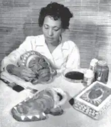 Black woman in white coat working on clay masks