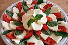 the bright red, pure white, and dark green ingredients are arranged on a plate to look somewhat like a flower