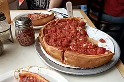 A large Chicago-style pizza with pieces cut from it