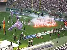 Players run by flares on the field