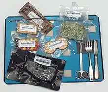 Space food: Cheddar spread, spinach, cookies, peanuts, crackers, steak, and utensils