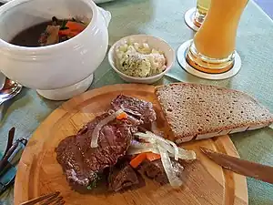 Kronfleisch in root stock. Garlic butter, grated horseradish and chopped onions are served with bread. The Kronfleisch can be ordered medium or drawn through. The root broth is spooned at the end.