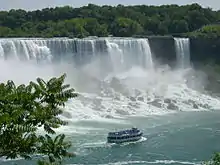 90 foot, three deck passenger vessel sails close to and parallel with huge waterfall