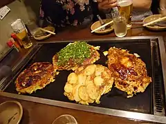 Okonomiyaki cooking on a teppan grill