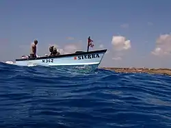 A Pirogue with divers and no radio about to pick up the diver in the water.