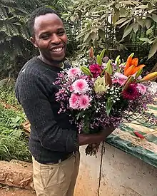 A smiling man holds a large bouquet of mixed flowers