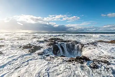 A picture of foamy surf spilling into a rocky hole.